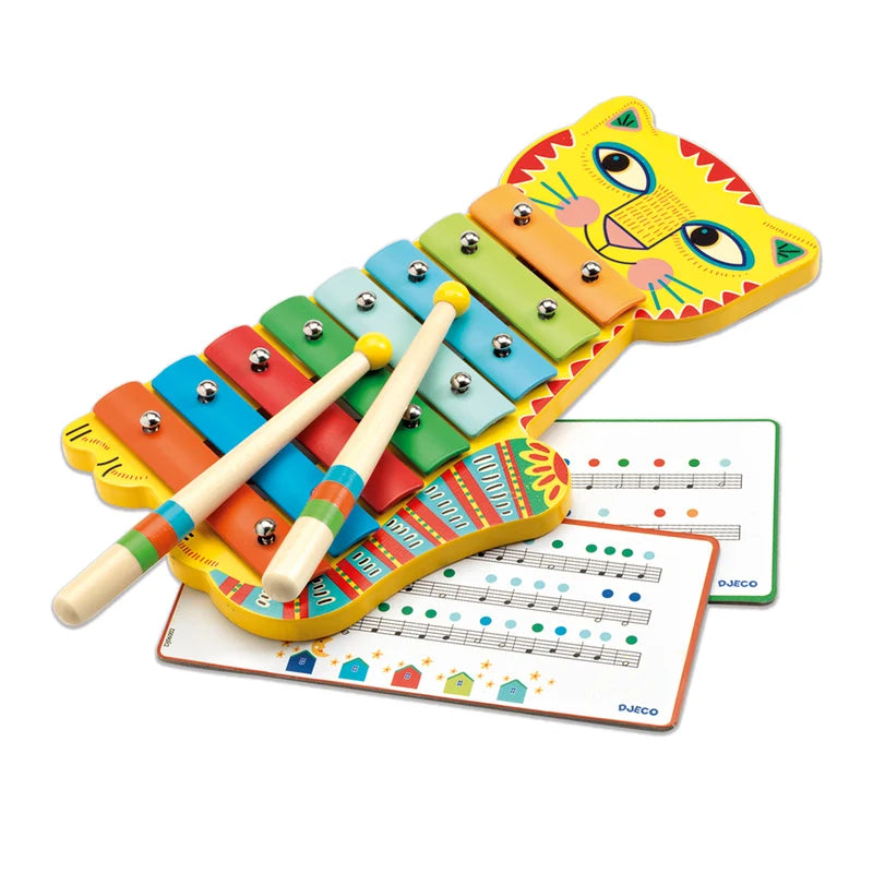 Métallophone chat coloré Djeco avec deux baguettes en bois posées sur les lames métalliques et deux cartes de partitions d'initiation à la musique.