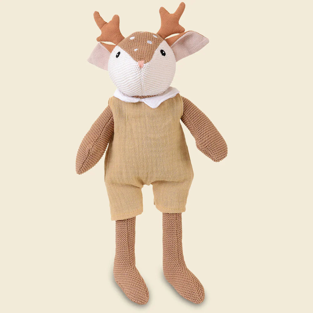 Peluche en tricot Woody le faon de Egmont Toys, portant une barboteuse beige en gaze de coton et un petit col blanc.