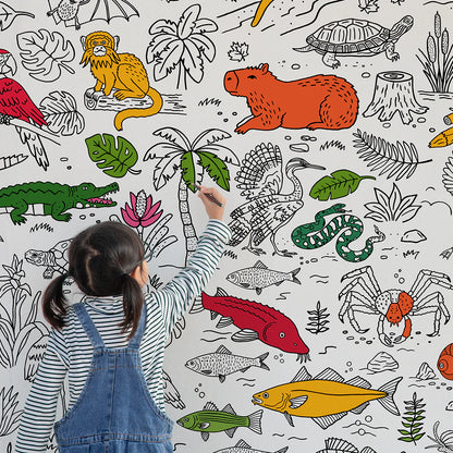 Texte alt : Une enfant de dos colorie les détails d'animaux sauvages sur l'affiche géante Écosystèmes des Amériques de Paperole.
