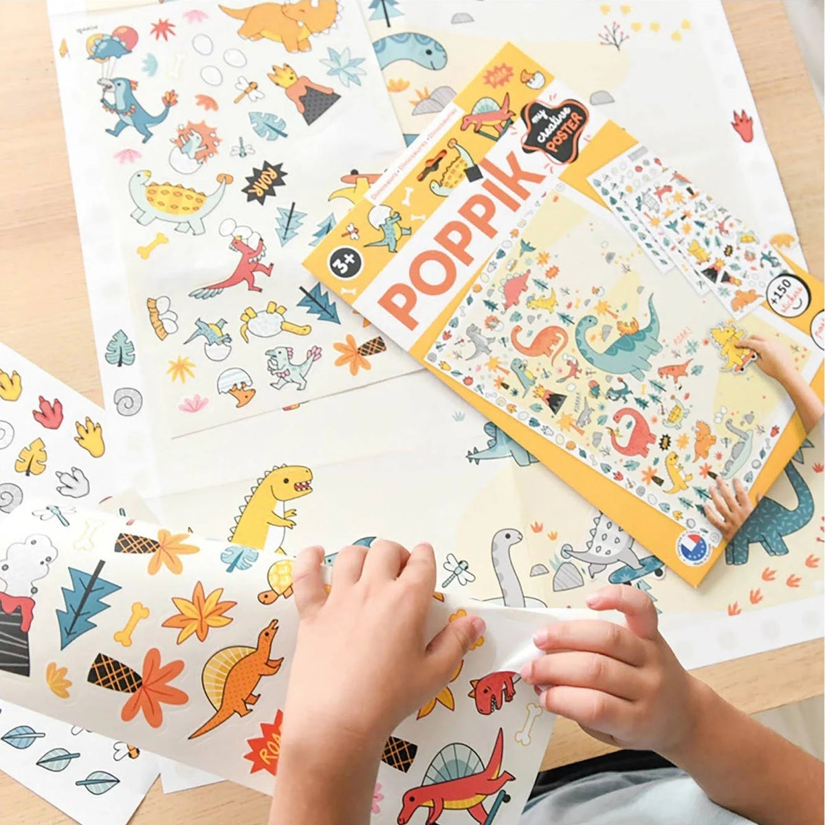 Enfant décollant des autocollants de dinosaures colorés pour compléter le poster géant de loisir créatif Poppik.