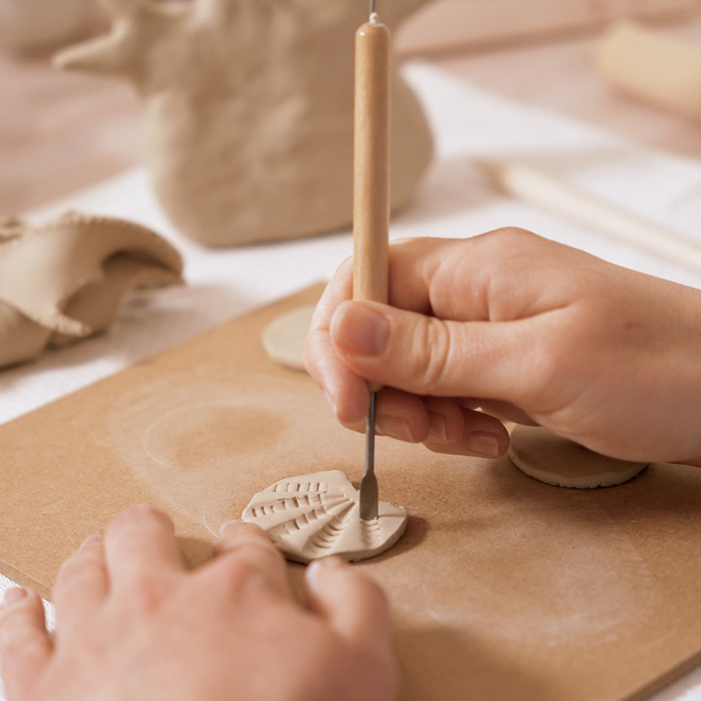 Gros plan sur le façonnage des détails d'un coquillage en argile à l'aide d'un mirette et d'un outil de modelage.