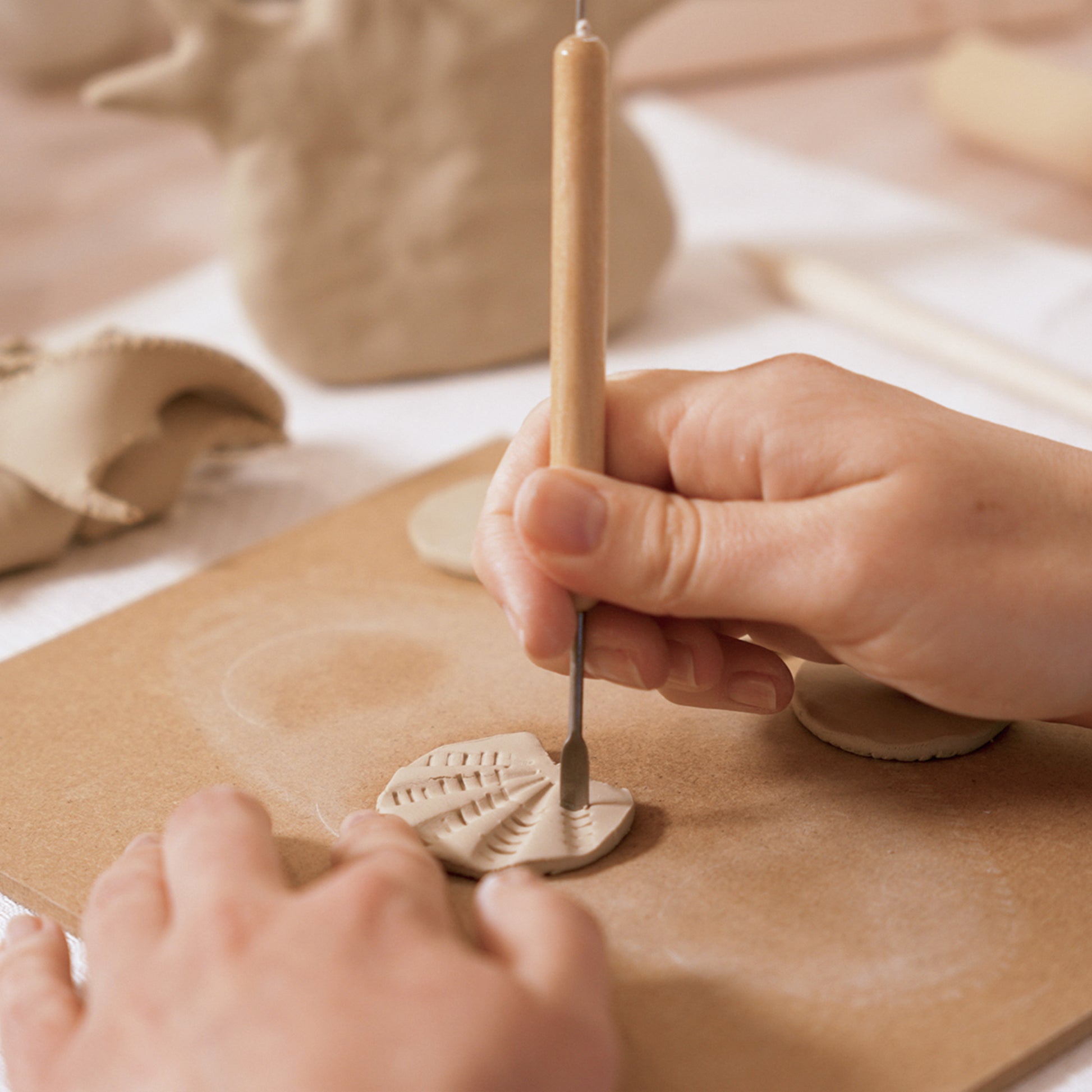 Gros plan sur le façonnage des détails d'un coquillage en argile à l'aide d'un mirette et d'un outil de modelage.