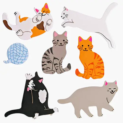 Gros plan sur les autocollants de chats de différentes couleurs (calico, gris, roux, noir) et une pelote de laine.