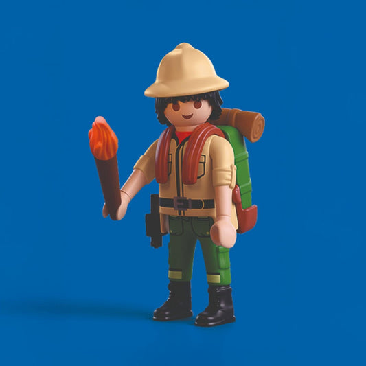 Figurine d'aventurier Playmobil vêtu d'un casque colonial et d'un sac à dos, tenant une torche enflammée.