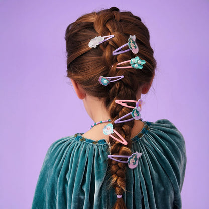 Jeune fille vue de dos avec une longue tresse française décorée de plusieurs barrettes à cheveux rose et violettes de la collection Plume par Djeco, sur le thème de la mer et des sirènes.