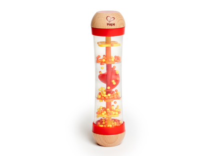 Bâton de pluie musical en bois et plastique transparent Hape garni de petites billes colorées rouges et jaunes.