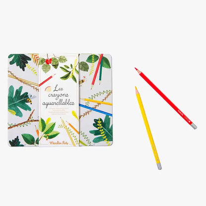 Boîte en métal illustrée de la collection Le Jardin du Moulin de Moulin Roty contenant 24 crayons aquarellables, présentée avec un crayon rouge et un jaune posés à côté.