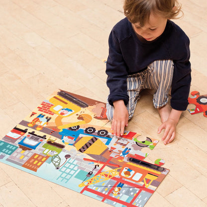 Enfant assis au sol en train d'assembler les grandes pièces du casse-tête géant Chantier de construction Petit Collage.