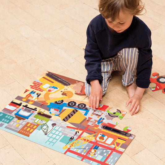 Enfant assis au sol en train d'assembler les grandes pièces du casse-tête géant Chantier de construction Petit Collage.