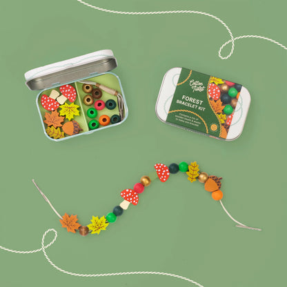 Kit de fabrication de bracelet en bois thème Forêt Cotton Twist présenté dans sa boîte métallique de rangement avec perles en formes de champignons, feuilles et glands.