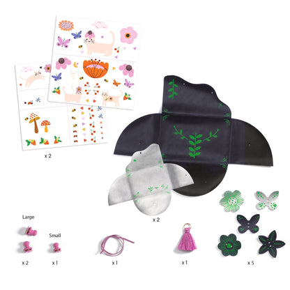 Contenu du coffret créatif Djeco comprenant deux pochettes à assembler, décalcomanies, fermoirs, pompon et breloques.