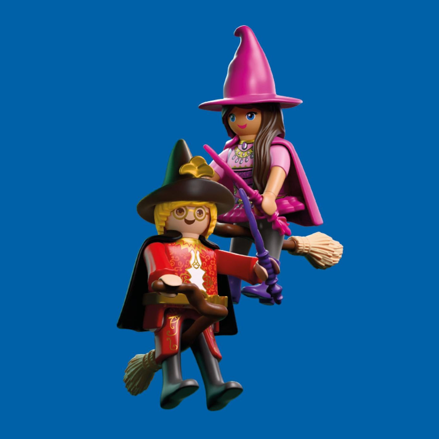 Figurines Playmobil d'un sorcier en tenue rouge et d'une sorcière en tenue rose volant sur leurs balais magiques avec leurs baguettes.