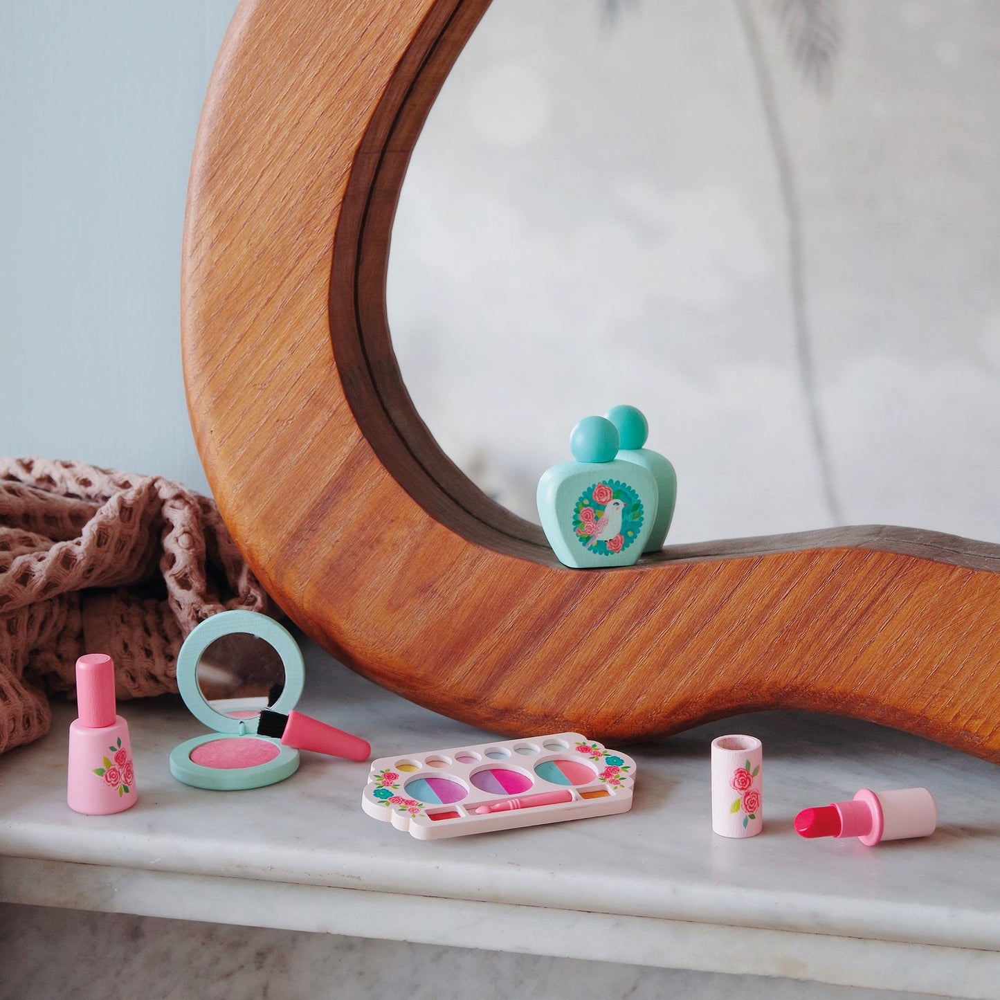 Ensemble de maquillage en bois Djeco disposé sur un meuble devant un miroir de coiffeuse.