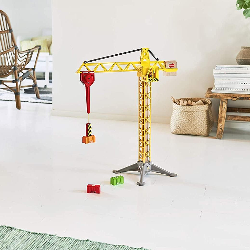 Grande grue lumineuse de chantier BRIO installée dans une pièce de séjour moderne avec ses conteneurs magnétiques au sol.