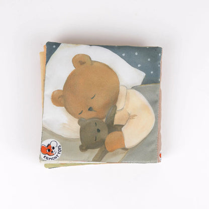 Couverture du livre d me tissu pour bébé Marcel l'Ours Egmont Toys montrant un ourson endormi avec son doudou.