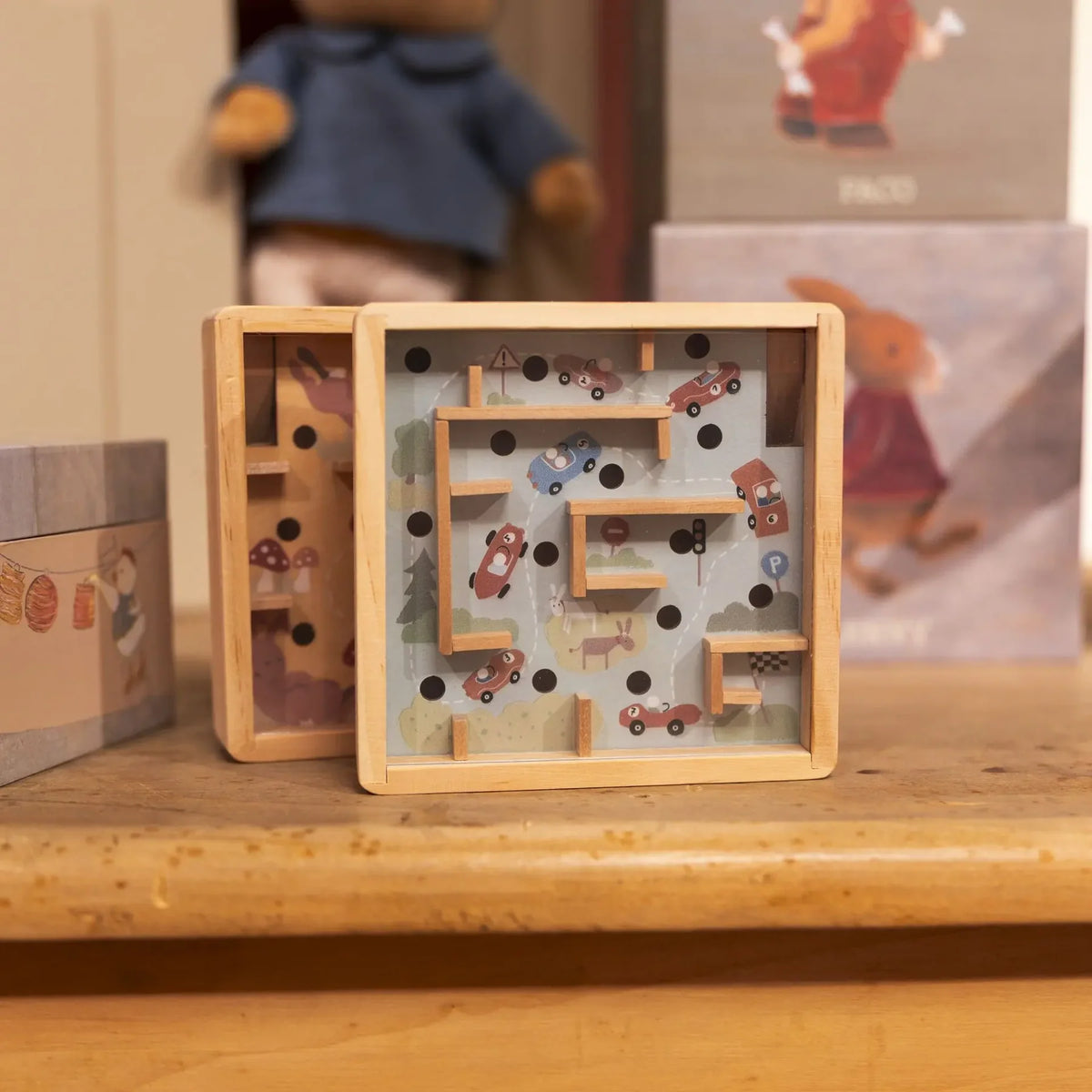 Deux mini-labyrinthes à billes en bois d'Egmont Toys posés sur une étagère, l'un sur le thème des voitures de course et l'autre sur le thème des lapins.