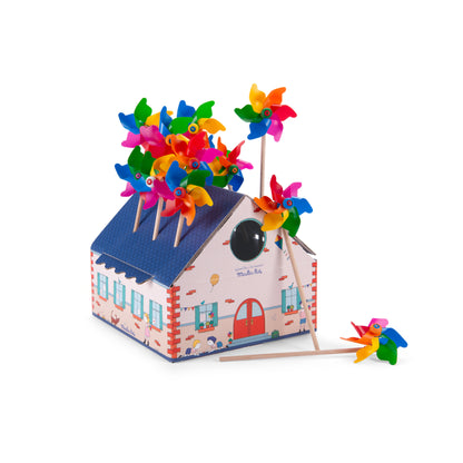Présentoir en carton en forme de maison de la collection Aujourd'hui c'est mercredi de Moulin Roty, rempli de moulins à vent multicolores en plastique montés sur des tiges en bois.