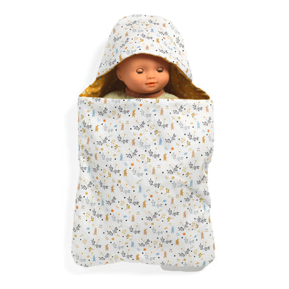 Poupée Pomea de Djeco endormie dans un nid d'ange rembourré à motifs floraux et capuche.