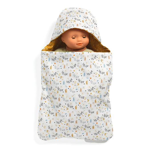 Poupée Pomea de Djeco endormie dans un nid d'ange rembourré à motifs floraux et capuche.