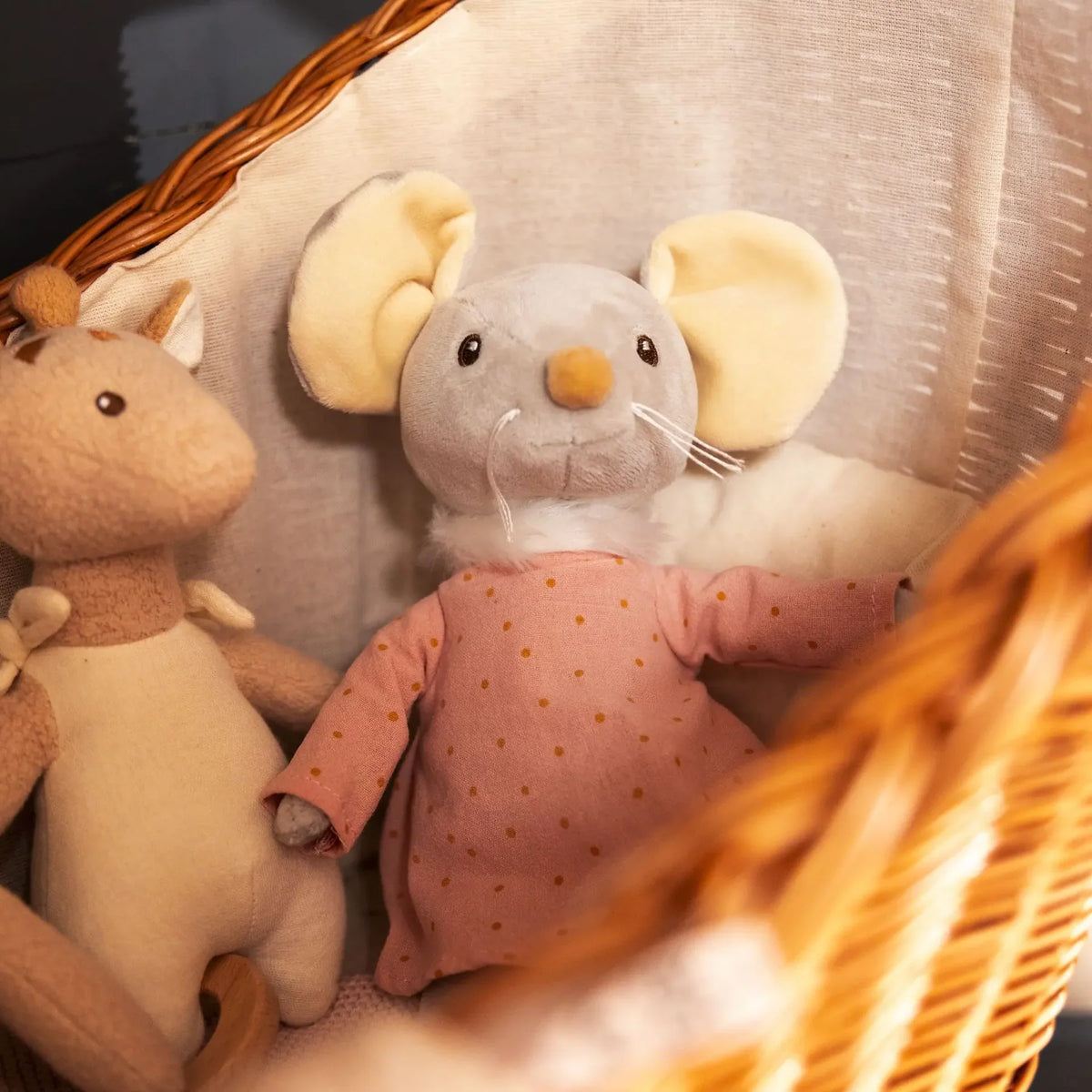 La peluche souris Agathe installée confortablement dans un couffin en osier.