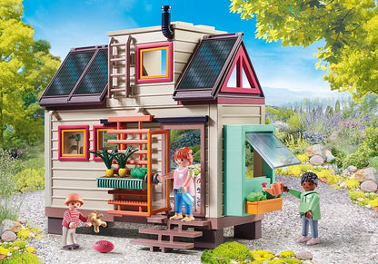 Façade extérieure de la petite maison écologique Playmobil avec panneaux solaires, bacs à fleurs et personnages.