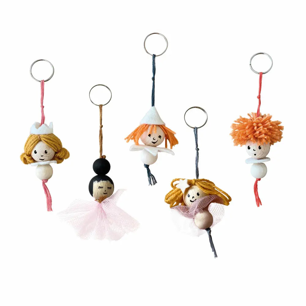 Cinq porte-clés faits main représentant de petites poupées en perles de bois, laine et tulle de la marque Egmont Toys.