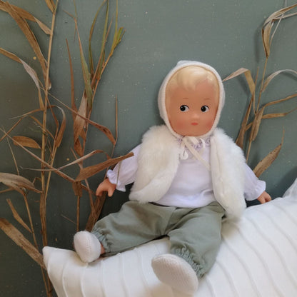 Poupon en vinyle Léa de la collection Les Petits Egmont Toys avec pantalon vert sauge et tenue d'hiver.