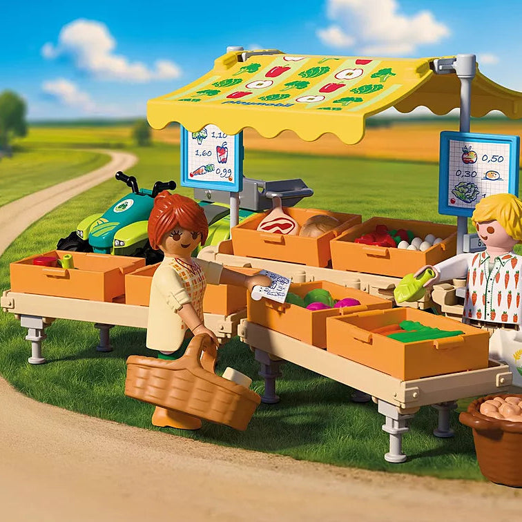Mise en scène du stand de légumes au marché Playmobil Country 72164 avec deux figurines, des cagettes de fruits et légumes, et un quad vert en arrière-plan.