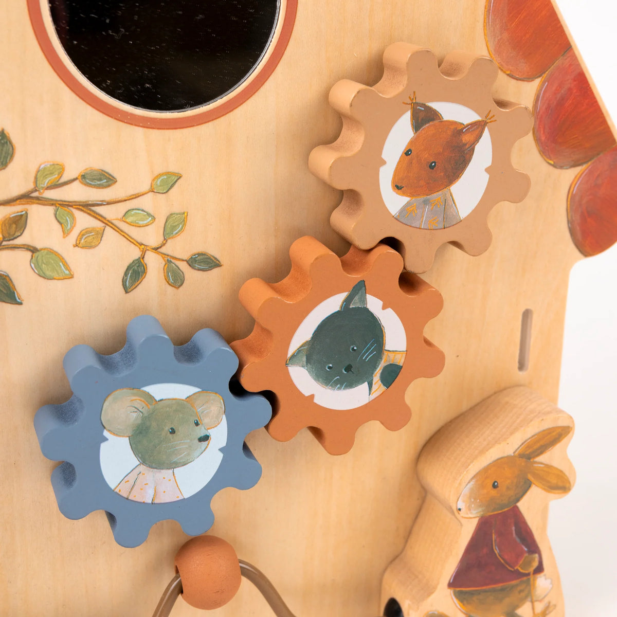 Gros plan sur les engrenages en bois bleus et orange d'un tableau d'éveil Egmont Toys, illustrés avec des têtes de souris, de chat et d'écureuil.
