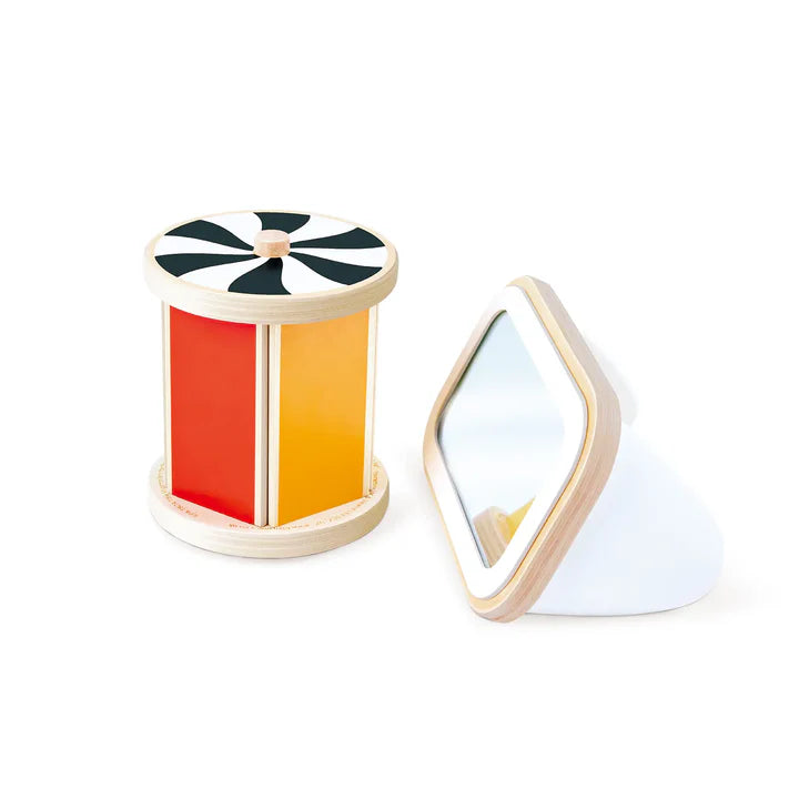 Le jouet d'éveil en bois Tambour rotatif avec miroir de Hape démonté, montrant ses faces colorées rouge et jaune, son dessus en spirale noire et blanche, ainsi que le petit miroir amovible.