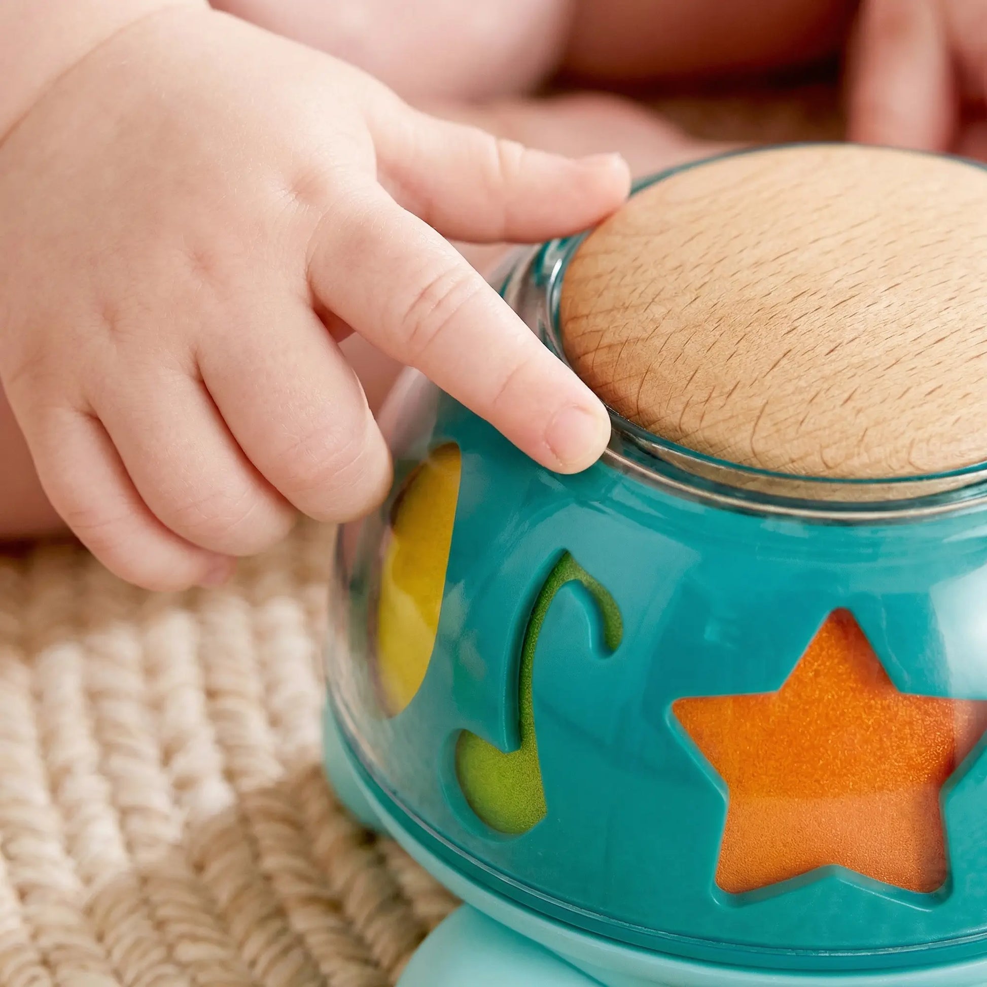 Gros plan sur la main d'un bébé touchant la carapace rotative de la tortue musicale Hape.