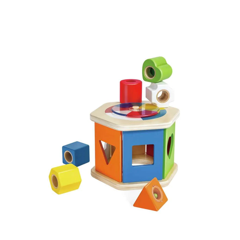 Trieur de formes hexagonal en bois Hape avec des blocs géométriques colorés à encastrer et un disque rotatif au sommet.